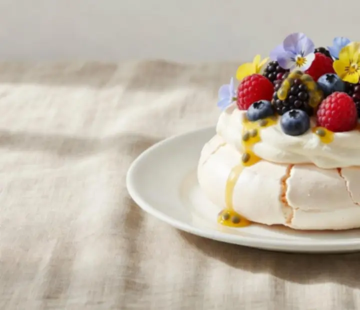 Whipped pavlova dessert topped with fresh fruit on a refined plate